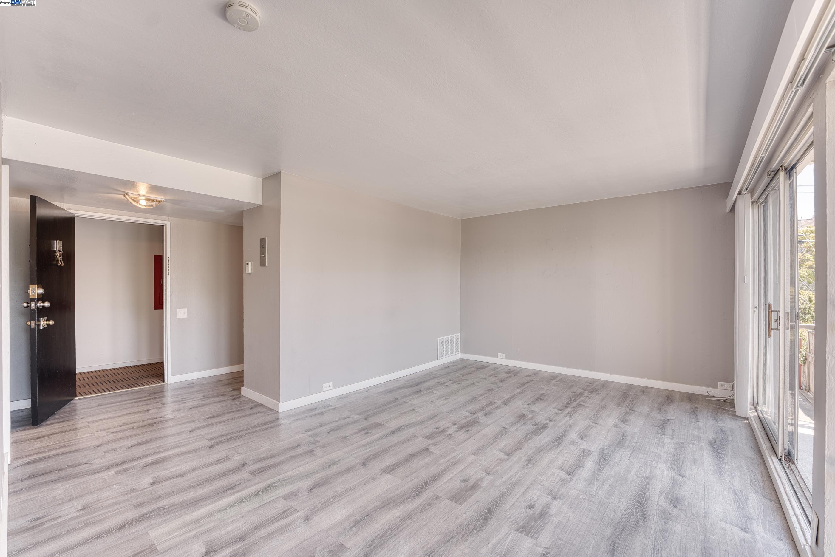 3815 Harrison Street, Unit 103 Oakland, CA 94611 - Photo 7 of 28 a view of an empty room with wooden floor and a window