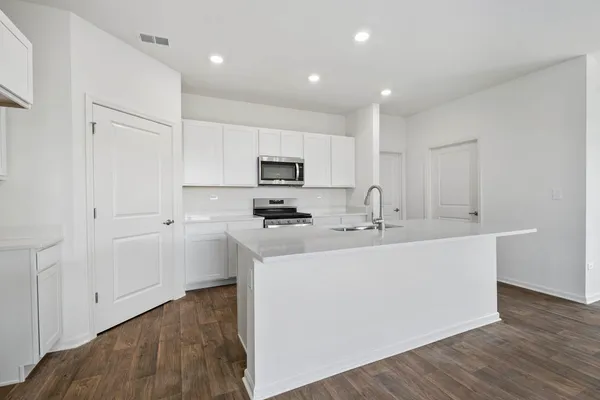 a kitchen with stainless steel appliances a sink a stove a microwave a center island and cabinets
