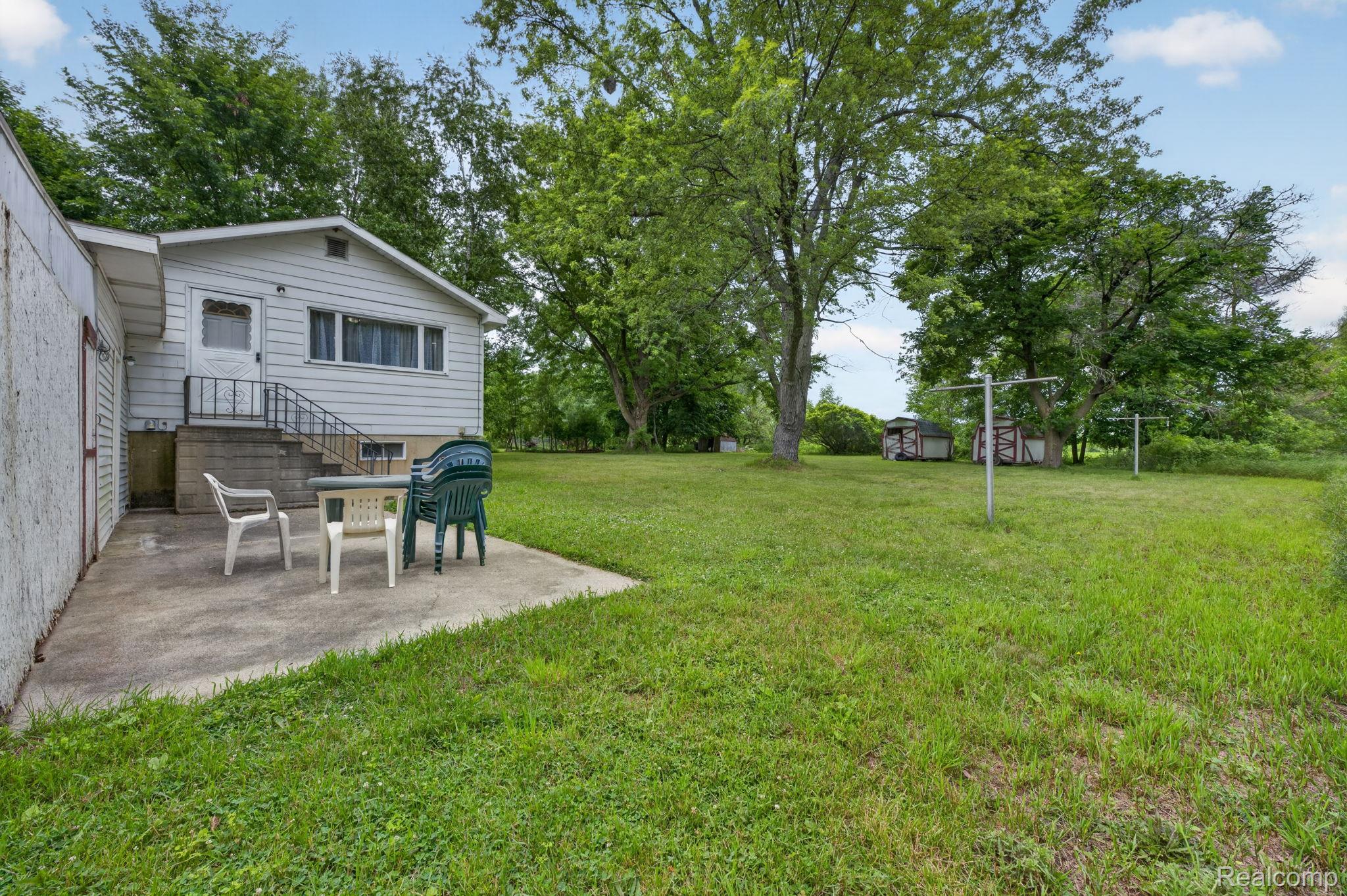 9288 Hilda Lane Flushing, MI 48433 - Photo 38 of 50 Expansive green lawn with mature trees and a concrete patio