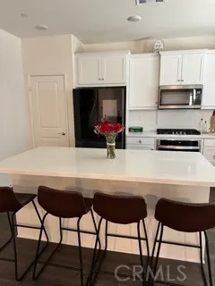 a kitchen with stainless steel appliances a table chairs refrigerator and sink