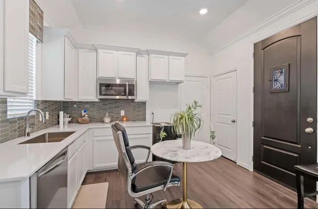 a kitchen with stainless steel appliances a dining table chairs and cabinets