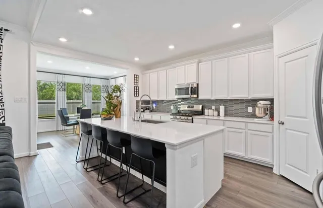a kitchen with a sink stove cabinets and wooden floor