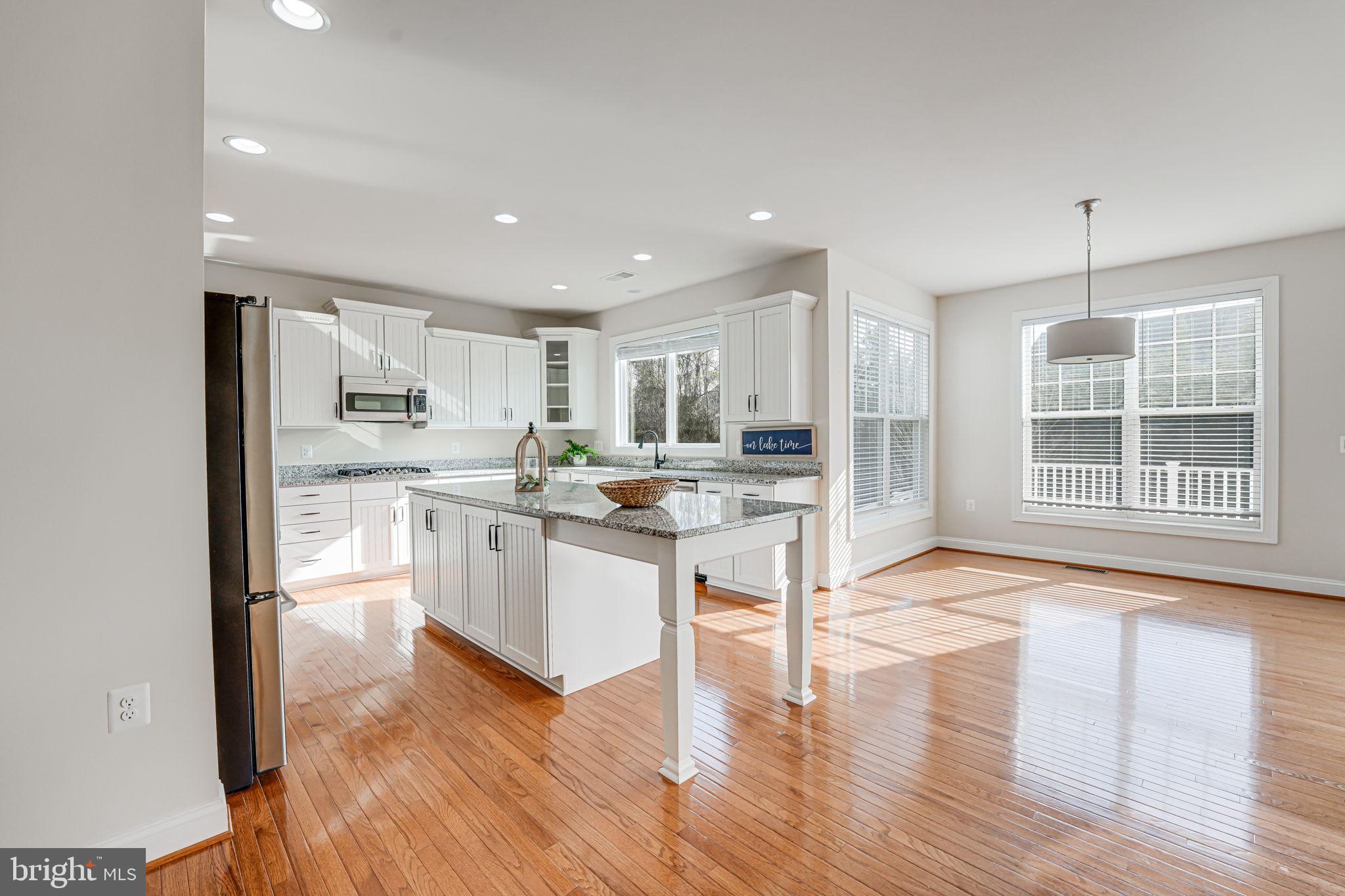 11708 Eagle Ridge Drive Spotsylvania, VA 22551 - Photo 14 of 75 a kitchen with stainless steel appliances kitchen island granite countertop a stove a sink a refrigerator and white cabinets with wooden floor