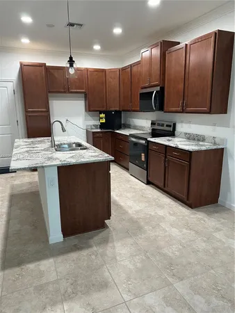 a kitchen with stainless steel appliances granite countertop a stove a sink a refrigerator and a microwave