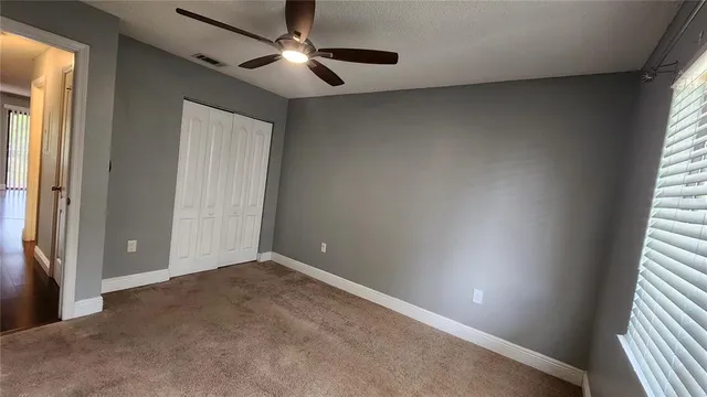 an empty room with a window and a fan