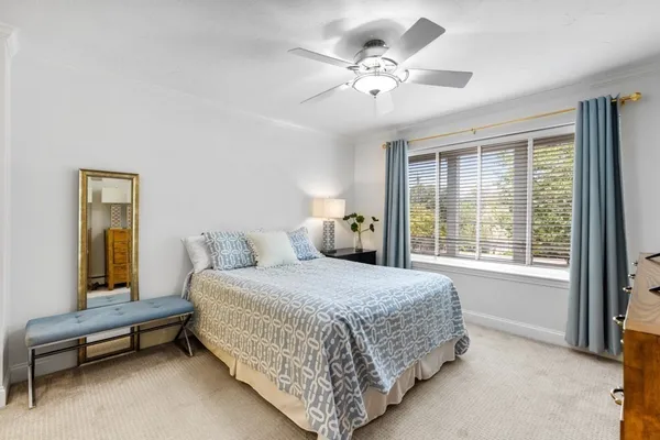 a bedroom with a bed television on desk and a window