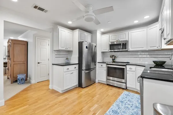 a kitchen with granite countertop white cabinets and stainless steel appliances