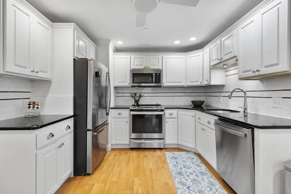 a kitchen with stainless steel appliances granite countertop a stove a sink dishwasher a refrigerator and a microwave oven with wooden floor