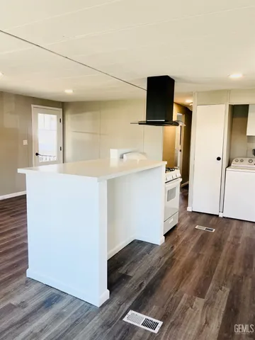 a kitchen with kitchen island a stove and a wooden floor