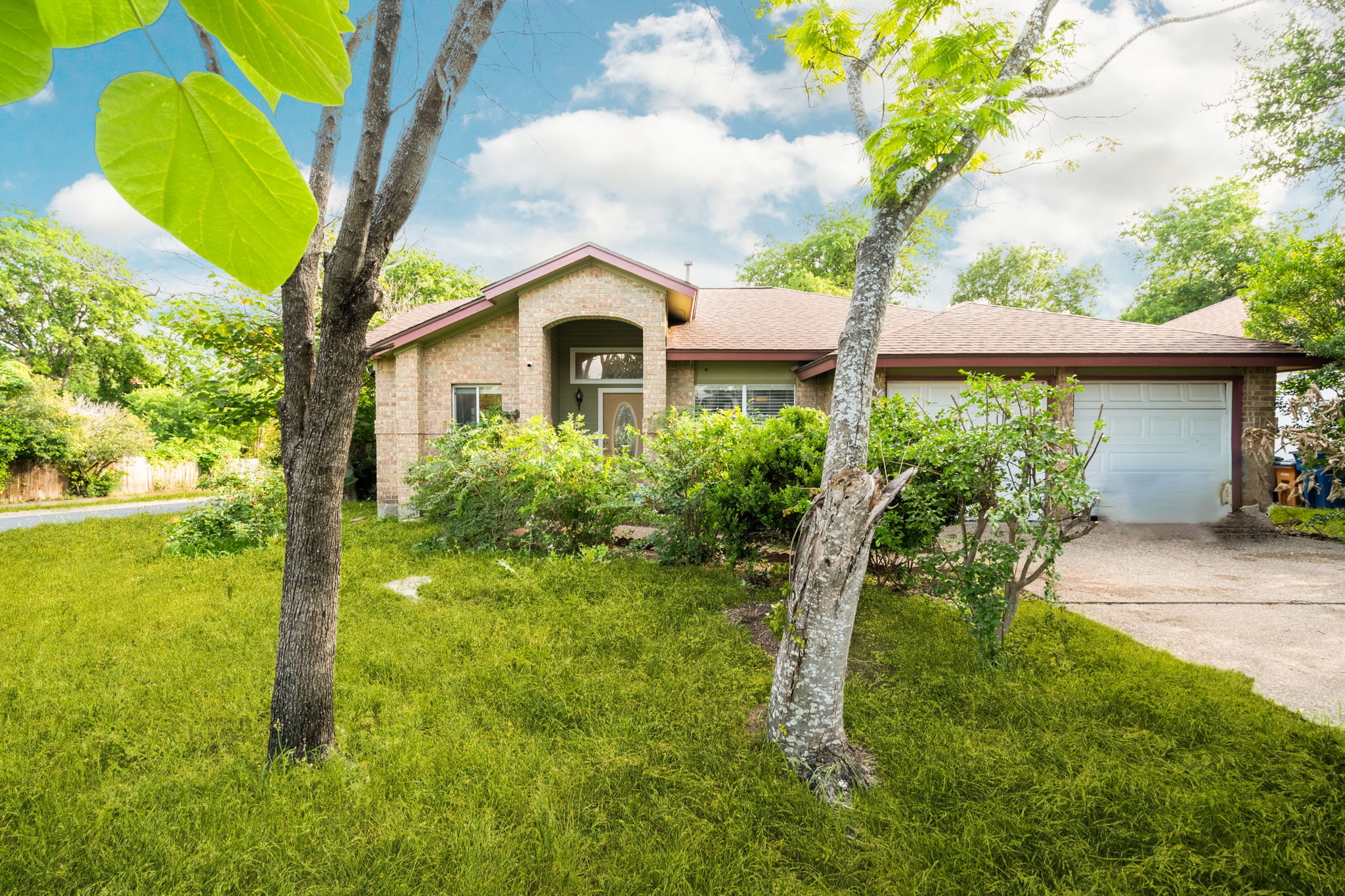 Ranch-style home featuring an attached garage, a front yard, brick siding, and driveway