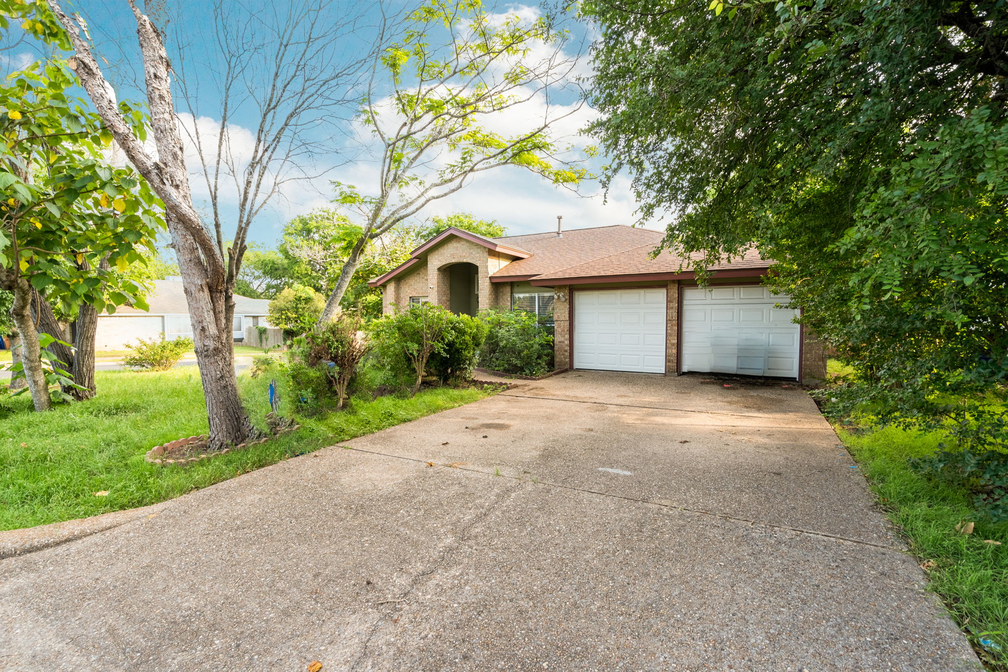 5611 Meadow Crest Austin, TX 78744 - Photo 2 of 26 View of front of home featuring a garage, driveway, brick siding, a front lawn, and a shingled roof
