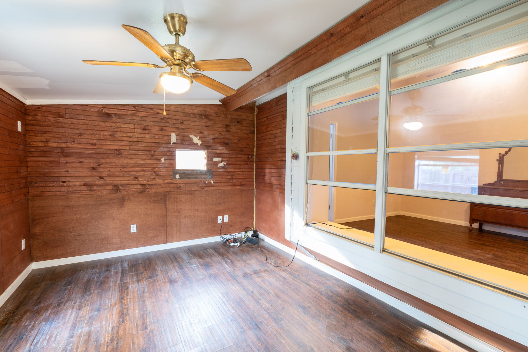 5611 Meadow Crest Austin, TX 78744 - Photo 24 of 26 Empty room featuring dark wood-style floors, wooden walls, vaulted ceiling, a ceiling fan, and ornamental molding