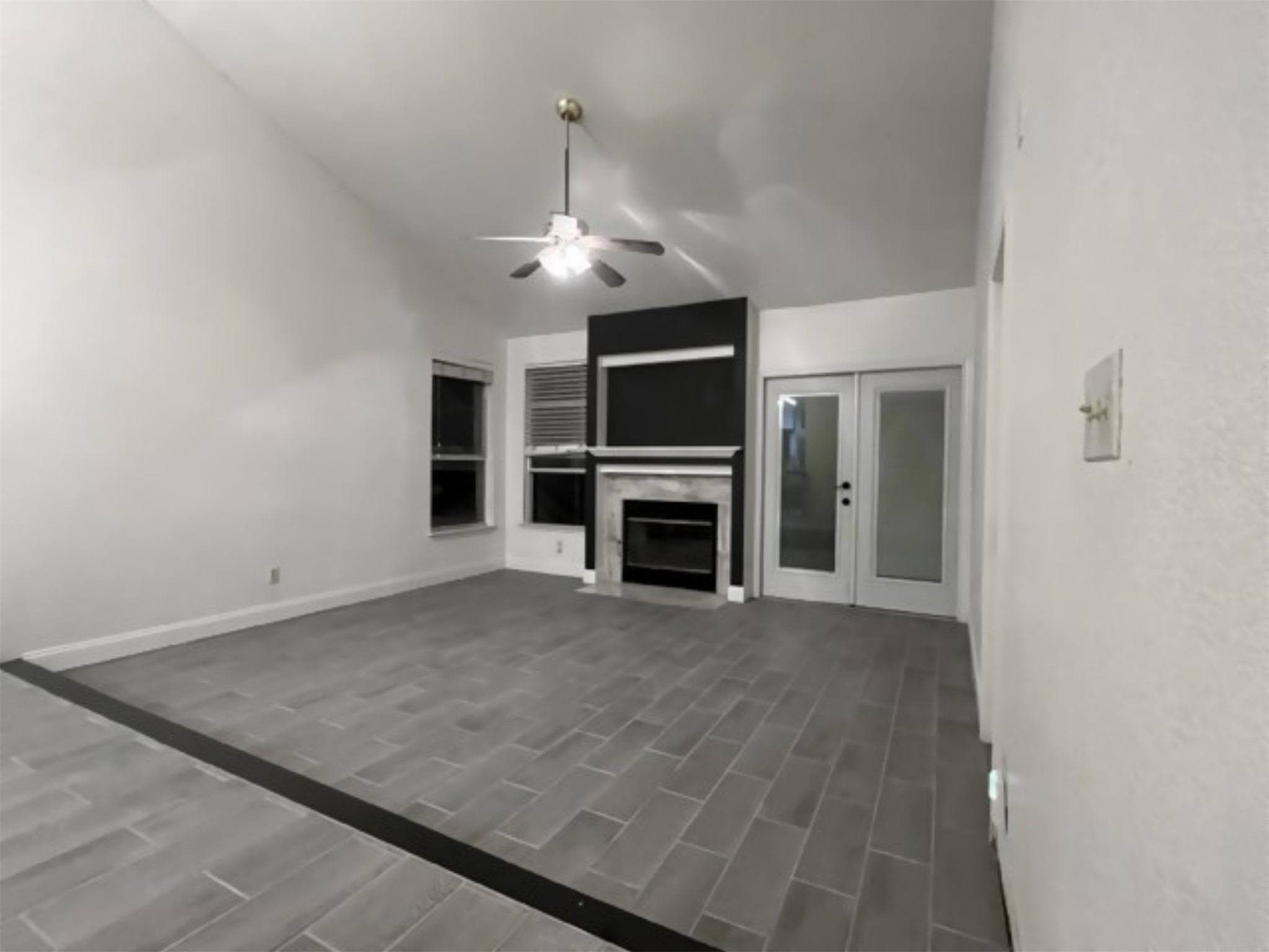 5611 Meadow Crest Austin, TX 78744 - Photo 5 of 26 Unfurnished living room with ceiling fan, a fireplace with flush hearth, and lofted ceiling