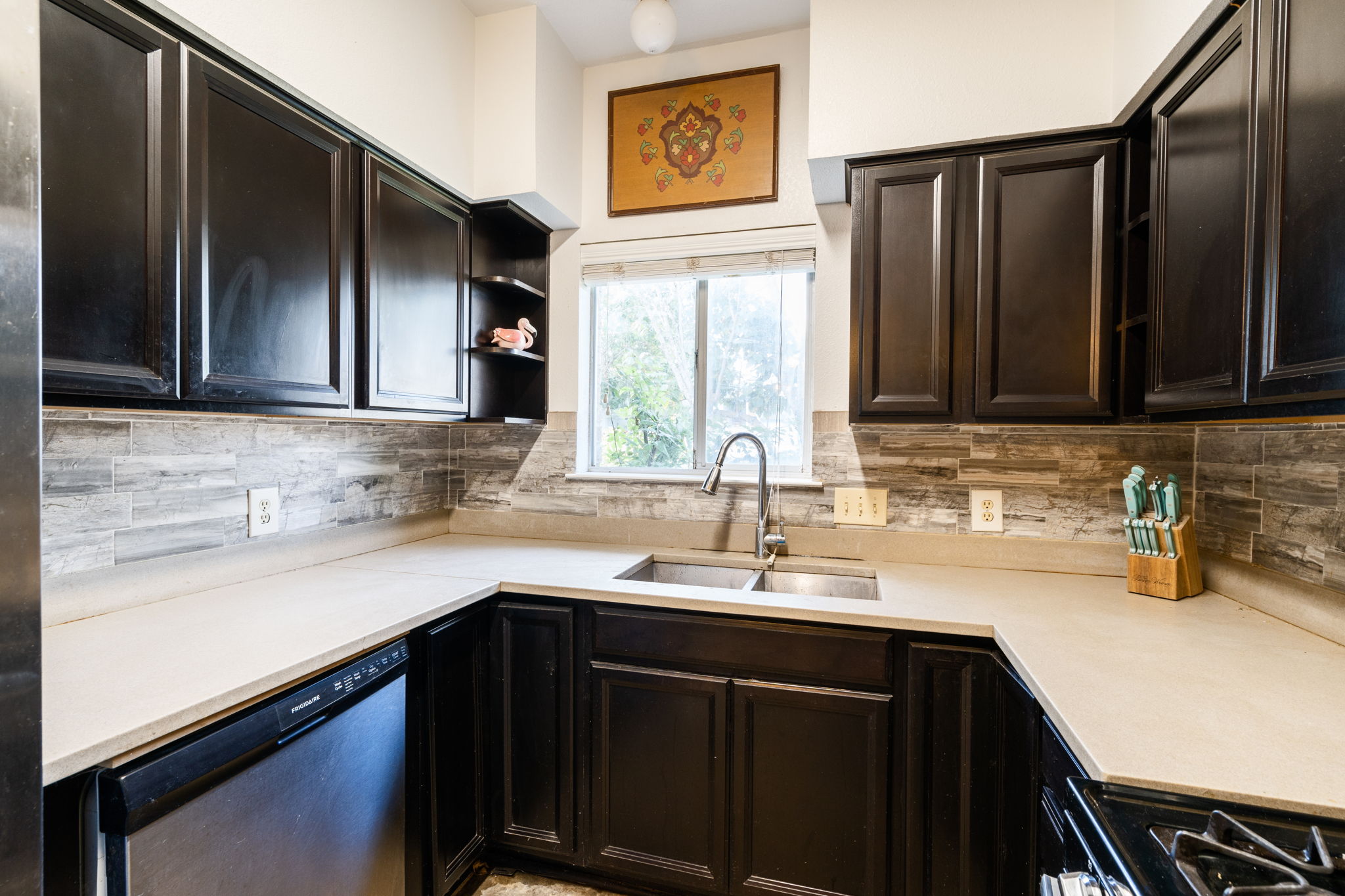 5611 Meadow Crest Austin, TX 78744 - Photo 7 of 26 Kitchen featuring stainless steel dishwasher, black gas stove, dark wood finish cabinets, and tasteful backsplash