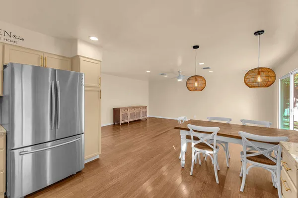 a kitchen with stainless steel appliances granite countertop a refrigerator a stove a sink dishwasher a dining table and chairs with wooden floor