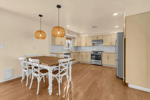 a view of a dining room and livingroom with furniture wooden floor a chandelier