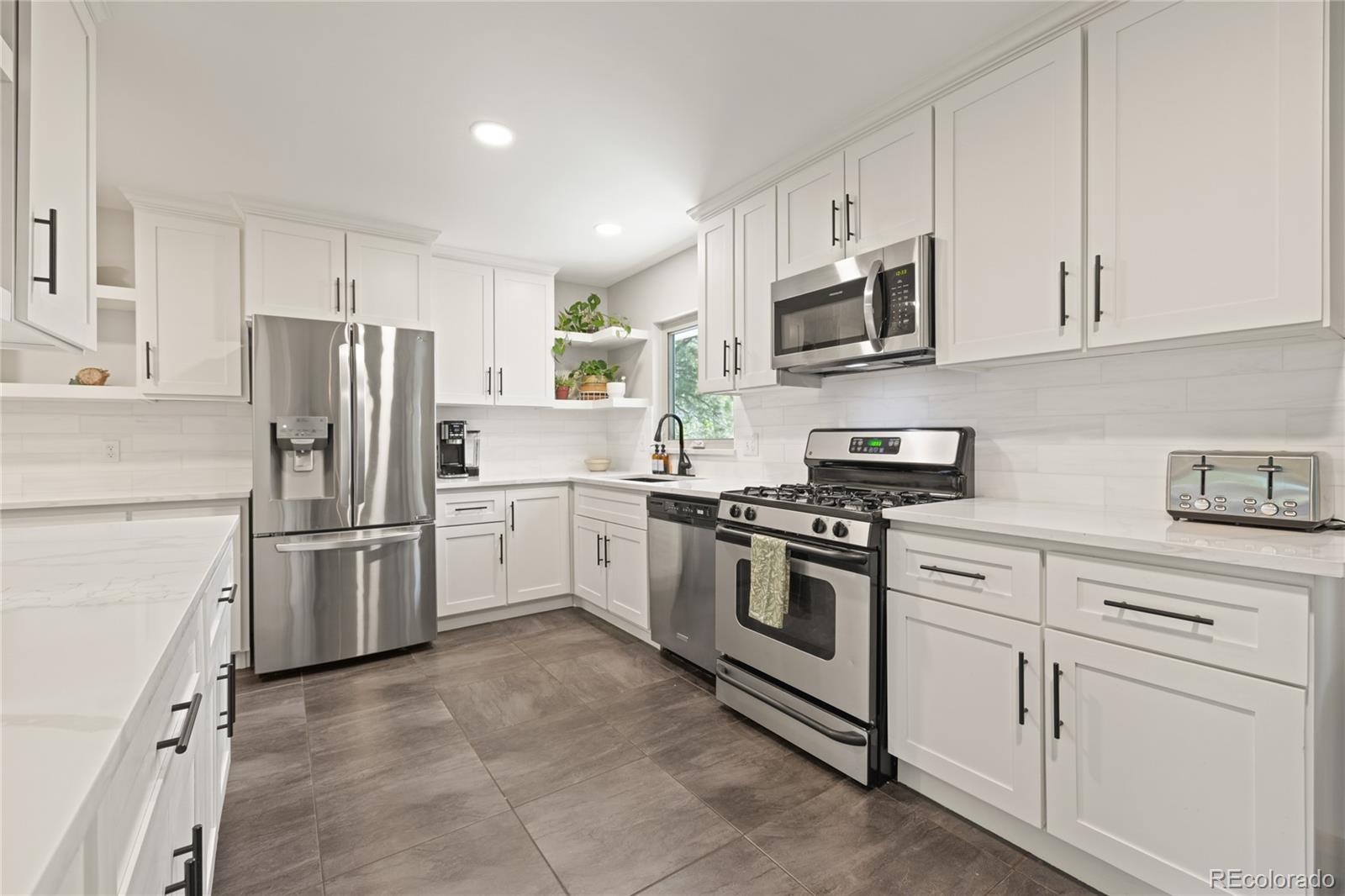 13402 West 24th Place Golden, CO 80401 - Photo 9 of 38 a kitchen with white cabinets and stainless steel appliances