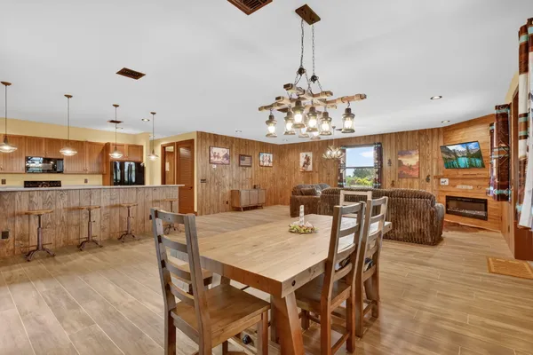 a view of a dining room and livingroom with furniture wooden floor a chandelier