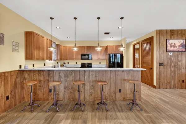 a view of a kitchen with kitchen island stainless steel appliances wooden floor and chair