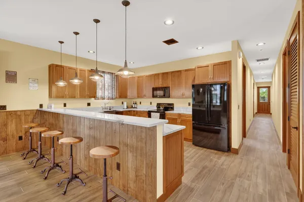 a view of a kitchen with kitchen island stainless steel appliances a stove a refrigerator a sink and a oven with wooden floor
