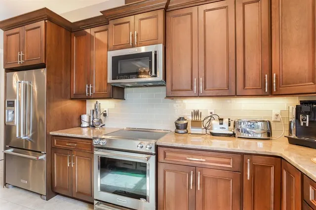 a kitchen with stainless steel appliances granite countertop a refrigerator stove and sink with wooden cabinets