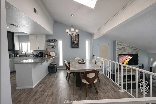 a kitchen with stainless steel appliances kitchen island granite countertop a dining table chairs and a refrigerator