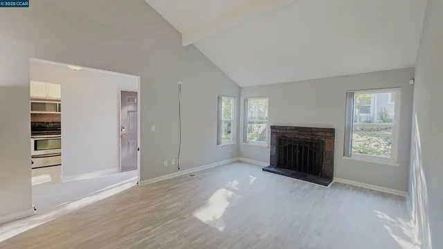 an empty room with windows and fireplace