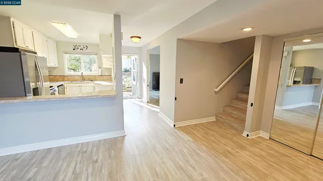 a living room with stainless steel appliances wooden floor and a large window