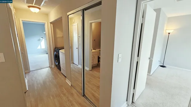 a view of a hallway with wooden floor and a bathroom