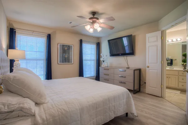 a bedroom with a bed a flat screen tv and a chandelier