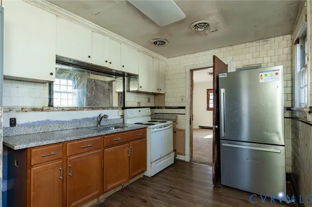 a kitchen with stainless steel appliances granite countertop a refrigerator a sink a stove and white cabinets