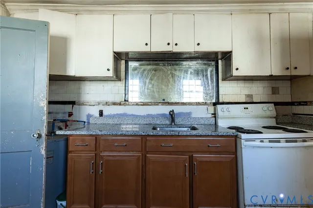 a kitchen with stainless steel appliances granite countertop a sink a stove and white cabinets