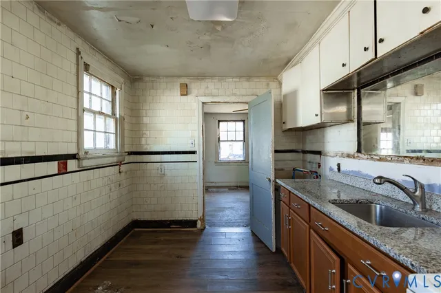 a kitchen with granite countertop a sink a counter top space and cabinets