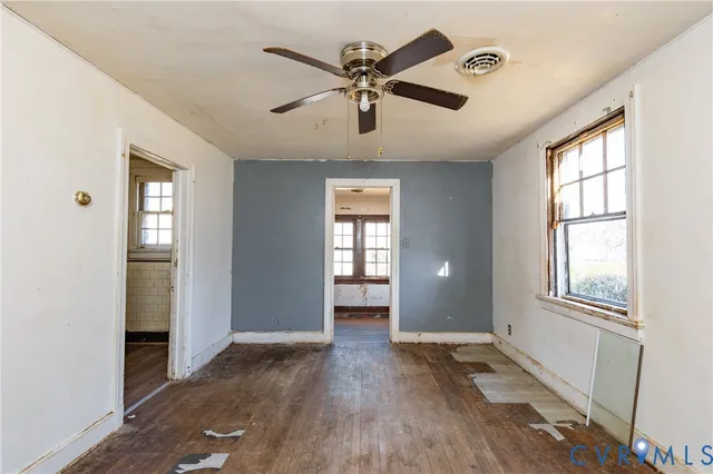 a view of an empty room with a window and wooden floor