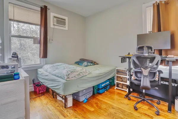 a bedroom with a bed next to a window with workspace