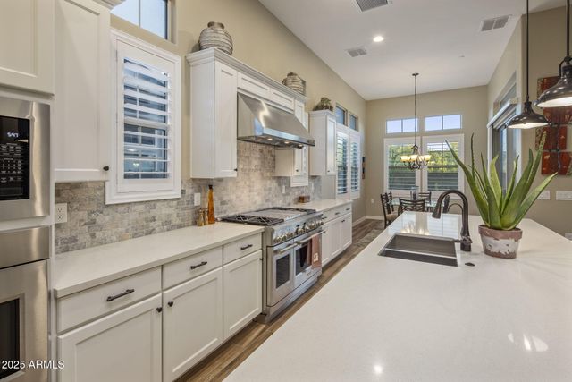 a kitchen with stainless steel appliances granite countertop a sink a stove and a wooden floors