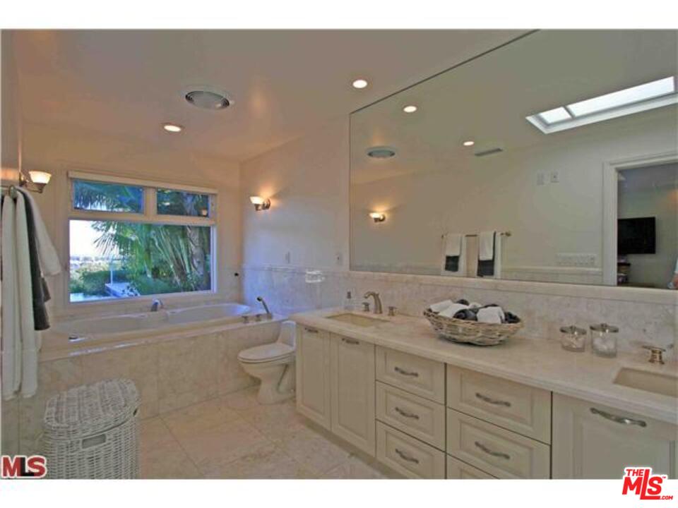 1148 Las Pulgas Road Pacific Palisades, CA 90272 - Photo 9 of 13 a bathroom with a granite countertop sink a toilet a large mirror and shower