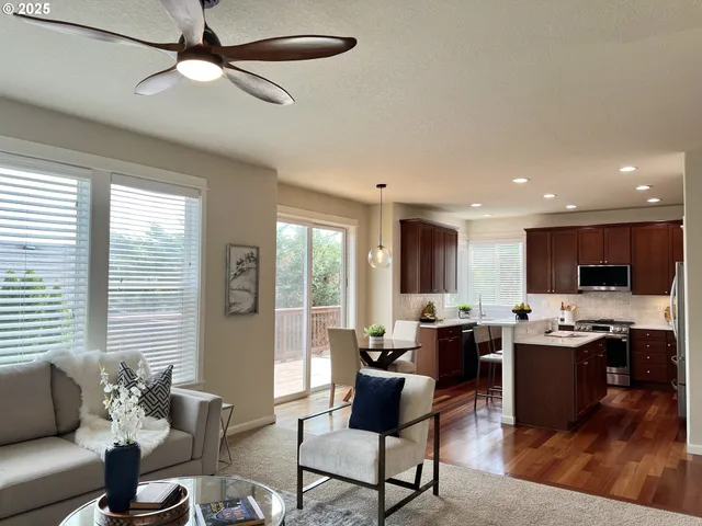 a living room with furniture kitchen view and a large window