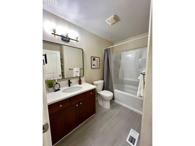 a spacious bathroom with a double vanity sink toilet mirror and bathtub