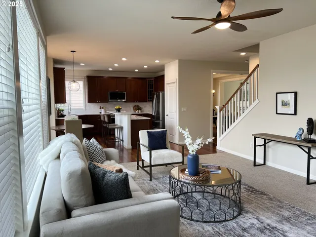 a living room with furniture kitchen view and a wooden floor