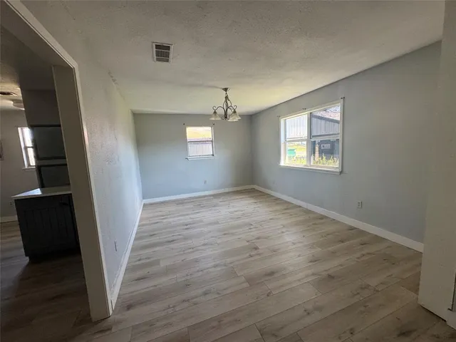 a view of an empty room with wooden floor and window