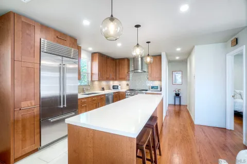 a large kitchen with stainless steel appliances kitchen island granite countertop a refrigerator a stove a sink and a wooden floors