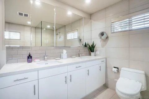 a bathroom with a double vanity sink toilet and a mirror