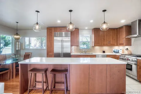 a kitchen with stainless steel appliances granite countertop a stove top oven a refrigerator a sink and a dining table with chairs