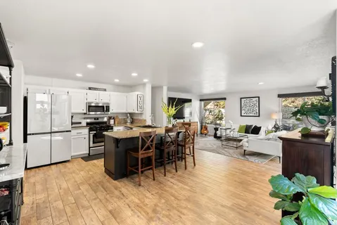 a kitchen with stainless steel appliances granite countertop a refrigerator a stove a sink a dining table and chairs