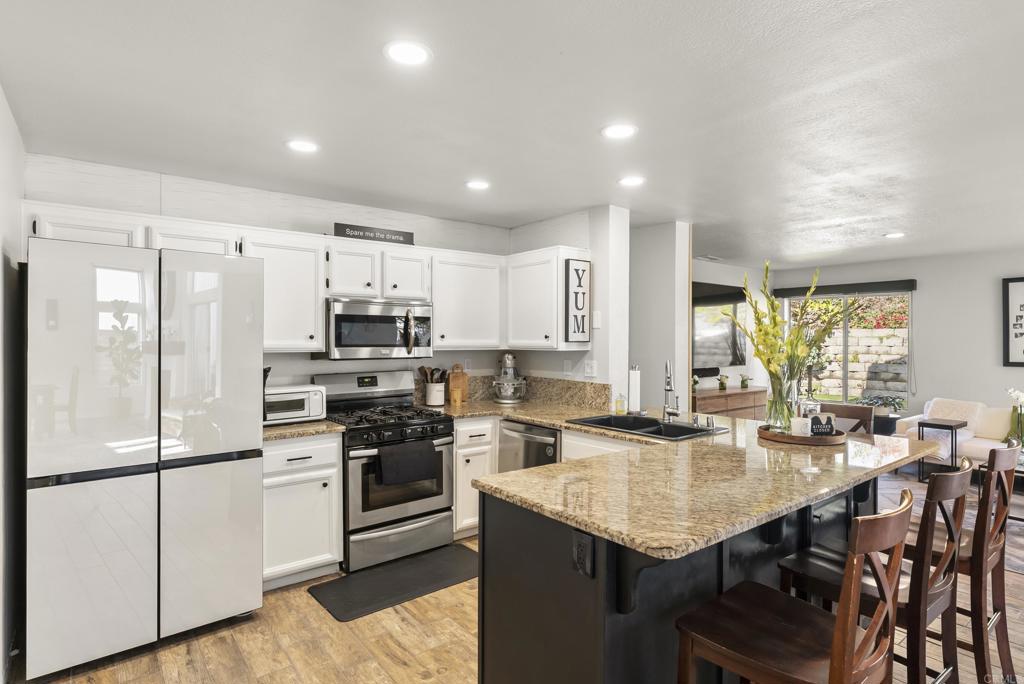 2225 Baxter Canyon Road Vista, CA 92081 - Photo 12 of 46 a kitchen with stainless steel appliances granite countertop a refrigerator a stove a sink a dining table and chairs