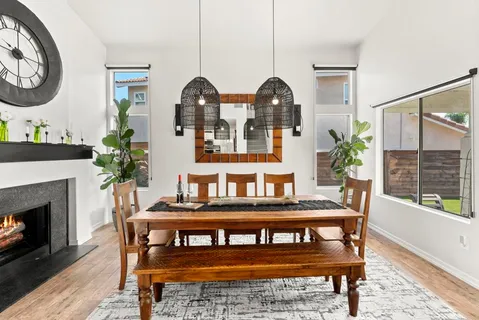 a kitchen with stainless steel appliances kitchen island granite countertop a refrigerator a stove a sink a dining table and chairs with wooden floor