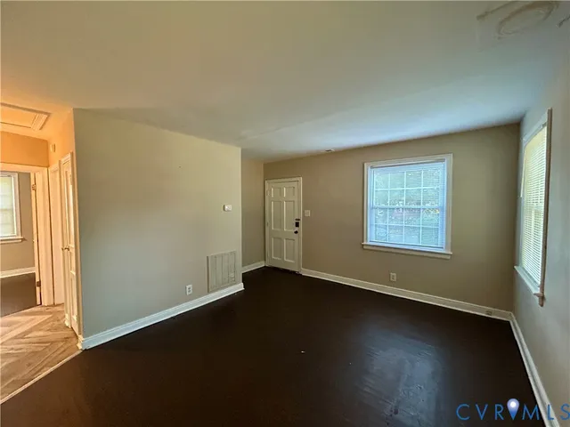 an empty room with wooden floor and windows