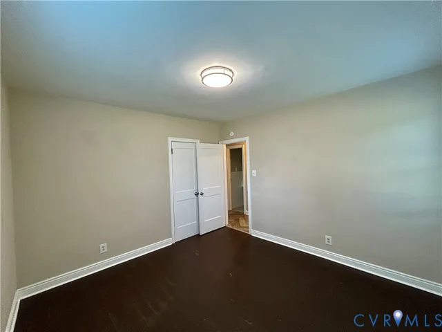 an empty room with wooden floor and natural light