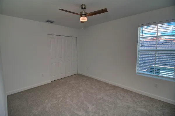 an empty room with a window and a ceiling fan
